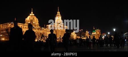 Menschen auf dem Bund in Shanghai, China bei Nacht vor dem Hintergrund von beleuchteten Gebäuden mit dem HSBC-Gebäude (links) und Custom House (Mitte). Stockfoto