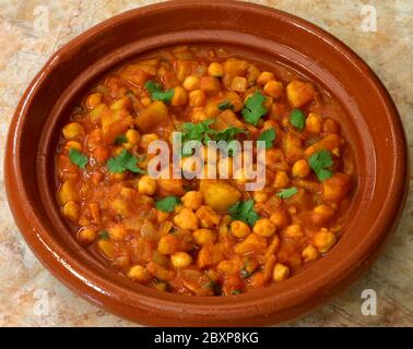 Chana Masala mit Süßkartoffeln. Würziges, vegetarisches Kichererbsencurry in einem Steingut-Gericht. Isoliert auf weißem Hintergrund. Stockfoto