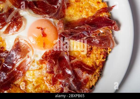 Isoliertes Bild von iberischer Schinkenpizza mit Ei. Selektiver Fokus. Luftaufnahme Stockfoto