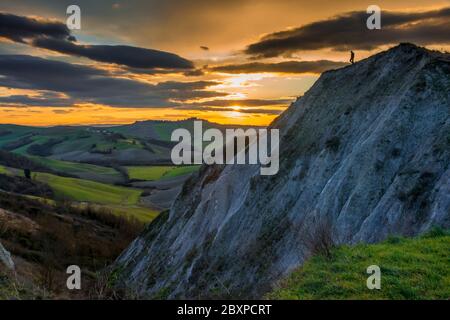 Ein einsamer Mensch geht allein auf einer Klippe bei Sonnenuntergang in der crete senesi Landschaft Stockfoto