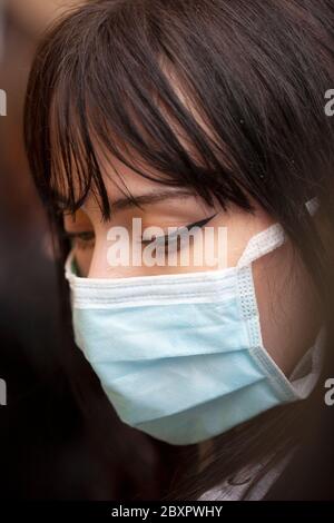 Junge Frau, Augen Make-up und eine chirurgische Gesichtsmaske, London England Großbritannien Stockfoto