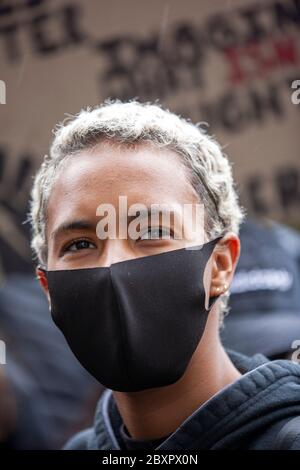 Junge blonde Frau, die eine schwarze Gesichtsmaske trägt, während der Proteste von Black Lives Matter UK am Parliament Square in London, England Stockfoto
