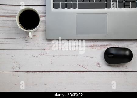 Notebook Wireless Maus und eine Tasse Kaffee auf dem weißen Tisch mit Kopierplatz. Stockfoto