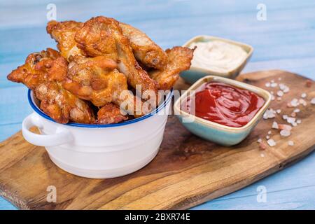 Gebratene Chicken Dippers in Eimer mit Sauce auf blauem Hintergrund.Chicken panierte Streifen in kleinen Keramik-Töpfe mit Ketchup und weiße Sauce . Stockfoto