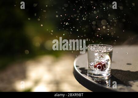 Rote Kirsche fallen in ein Glas Wasser produzieren Wasser Spritzer, frieren in der Zeit Foto, konzeptionell. Stockfoto
