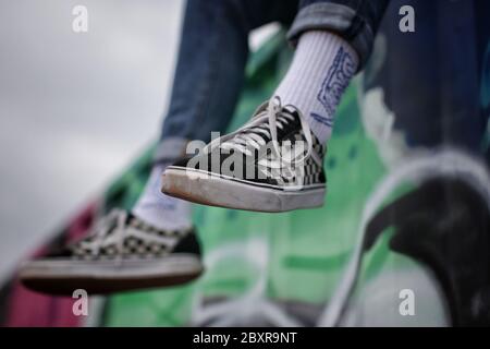 Mann in klassischen schwarz-weißen maschggrid Transporter Schuhe sitzen auf dem kommerziellen Container, Calgary, Kensington-Bereich Stockfoto