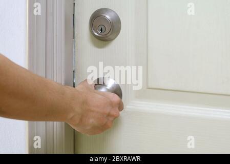 Die Hand des Mannes hält den Türknopf, um die Tür zu schließen Stockfoto