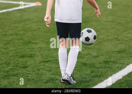 Fußballspieler beim Jonglieren eines Fußballs. Junger Junge Spielt Fußball. Sporttraining Feld im Hintergrund Stockfoto