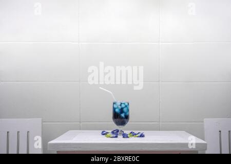 Schmetterlingserbsenauf einem pastellrosa Holztisch vor der Zementwand auf dem Außenfeld. Stockfoto