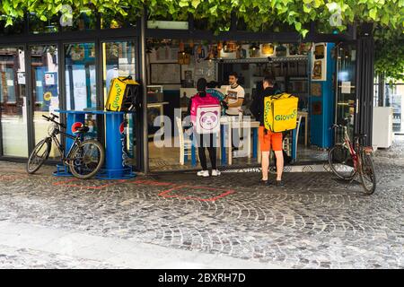 Food Panda und Glovo Lebensmittel-Lieferservice Kurier warten auf die Abholung der Bestellung in der Altstadt von Bukarest, Rumänien, 2020. Lebensmittellieferungen per Fahrradkurier wegen c Stockfoto