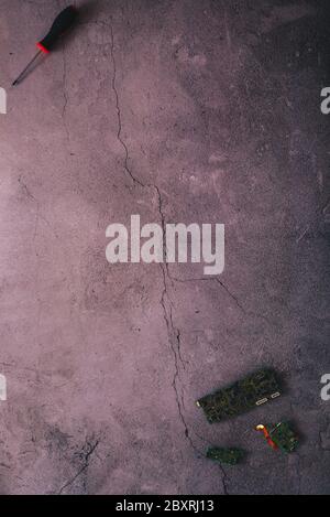 Flaches Einlegen einiger Mainboards und eines Schraubendrehers auf einem gesprungenen Betonhintergrund mit viel Kopierplatz Stockfoto