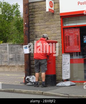 Ein Potman leert die Briefkasten im New Mills Post Office Stockfoto