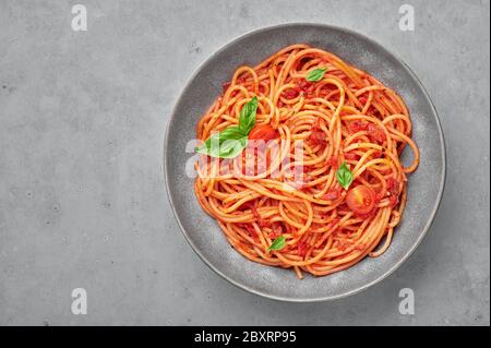 Tomatenspaghetti in grauer Schüssel auf betonierten Hintergrund. Tomatensauce Pasta ist klassische italienische Küche Gericht. Beliebte italienische Küche. Kopierbereich. Draufsicht Stockfoto