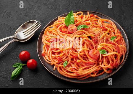 Tomatenspaghetti auf schwarzem Teller auf dunklem Schiefergrund. Tomatensauce Pasta ist klassische italienische Küche Gericht. Beliebte italienische Küche Stockfoto