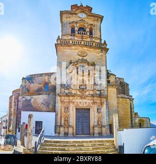 Der hohe Glockenturm der Kirche San Pedro, geschmückt mit Uhr, geschnitzten Steinmustern, Skulpturen von Heiligen und schlanken Säulen, Arcos, Spanien Stockfoto