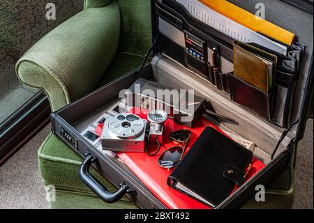 Technische Artikel der 1980er Jahre in Aktentasche inkl. Mobira Cityman Handy, Olympus O 35mm Kamera, Filofax Tagebuch, Fliegersonnenbrille, Checkbook & Stuhl Stockfoto