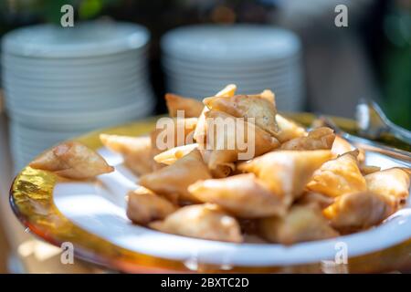 Ein Samosa ist ein gebratenes oder gebackenes Gebäck mit einer herzhaften Füllung, wie gewürzte Kartoffeln, Zwiebeln, Erbsen, Fleisch oder Linsen. Es kann verschiedene Formen annehmen, inkl. Stockfoto