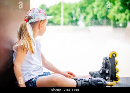 Nettes lächelndes kleines Mädchen auf Rollschuhe wegschauen Stockfoto