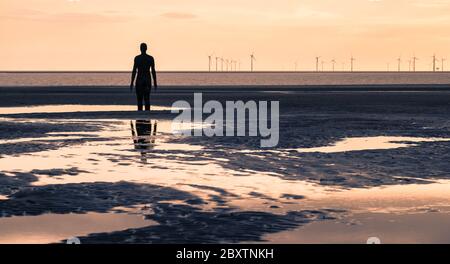 Einer der hundert Iron Men (von Antony Gormley geschaffen), der im Juni 2020 von der Crosby-Küste aus auf einen Windpark in der Irischen See blickte Stockfoto