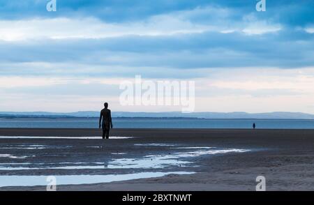 Zwei Eiserne Männer (erstellt von Antony Gormley), die im Juni 2020 in der Dämmerung von der Crosby-Küste (bei Liverpool) aus zur Irischen See blicken. Stockfoto