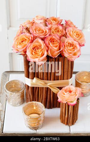 Blumenarrangement mit Rosen und Zimtstangen steht auf dem Tisch. Partydekor Stockfoto