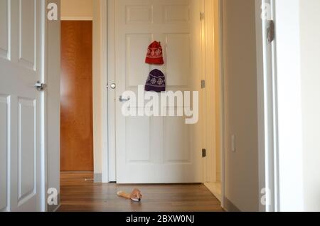 NACH DER SCHULE: Die Wintermützen der Kinder hängen an den Haken der Schranktür. Stockfoto