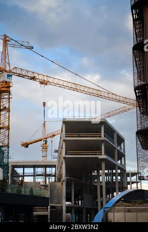 Betonbaustelle mit zwei Kranen. Blauer Himmel tagsüber auf der Anlage. Riesiger Kran, der zwischen zwei Gebäuden im Bau steht Stockfoto