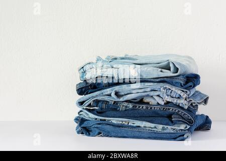 Ein Stapel von verschiedenen Jeans Hosen Nahaufnahme auf einem weißen Hintergrund, lässige Kleidung Stockfoto