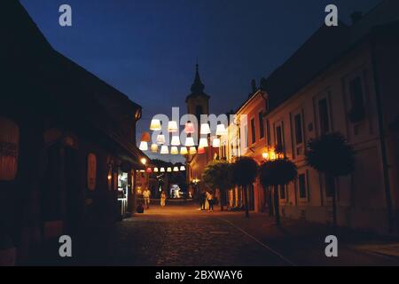 SZENTENDRE, UNGARN - 23. Juli 2019 - Nachtsicht auf das kunstvoll beleuchtete Stadtzentrum von Szentendre, ungarische Stadt voller Kunst- und Souvenirläden Stockfoto