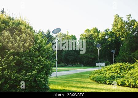 Kompakte Solarpaneele auf Straßenlaternen im grünen grünen Stadtpark, keine Menschen gesetzt. Nachhaltigkeit in der städtischen Umwelt. Stockfoto