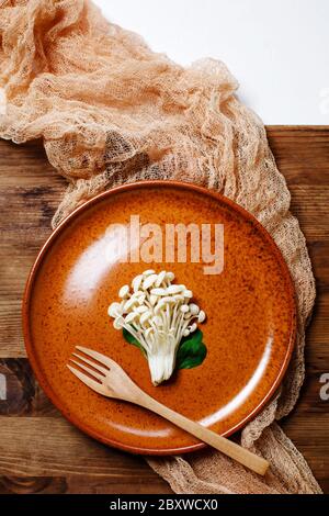 Enoki, Enokitake, Flammulina velutipes, essbare Pilze, die in der japanischen Küche beliebt sind. Haufen von kleinen weißen Pilzen auf Keramikplatte serviert, Diät, Stockfoto