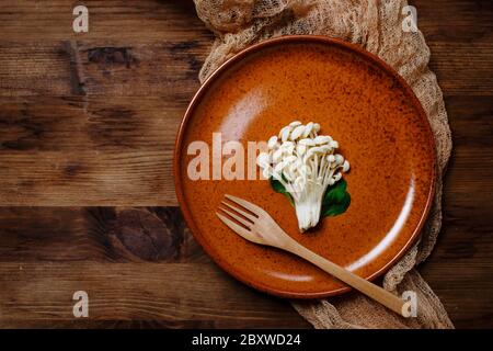 Enoki, Enokitake, Flammulina velutipes, essbare Pilze, die in der japanischen Küche beliebt sind. Haufen von kleinen weißen Pilzen auf Keramikplatte serviert, Diät, Stockfoto