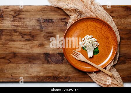 Enoki, Enokitake, Flammulina velutipes, essbare Pilze, die in der japanischen Küche beliebt sind. Haufen von kleinen weißen Pilzen auf Keramikplatte serviert, Diät, Stockfoto