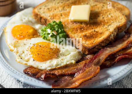 Hausgemachte Sunnyside Eier Frühstück mit Toast und Speck Stockfoto