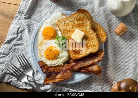 Hausgemachte Sunnyside Eier Frühstück mit Toast und Speck Stockfoto