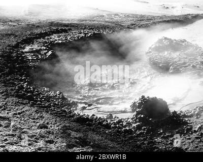 Dampf entweicht aus dem Schlammtopf und beleuchtet von Sonnenstrahlen, Sol de Manana, Altiplano, Bolivien, schwarz-weiß-Bild Stockfoto