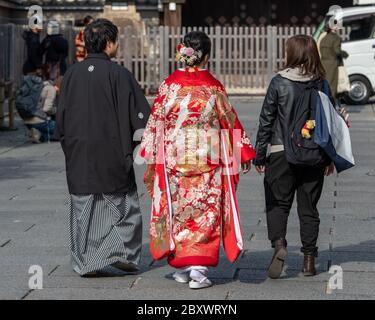 Japanisches Paar in traditioneller Kleidung, das mit einem Freund im alten Teil von Kyoto, Japan, spazierengeht Stockfoto