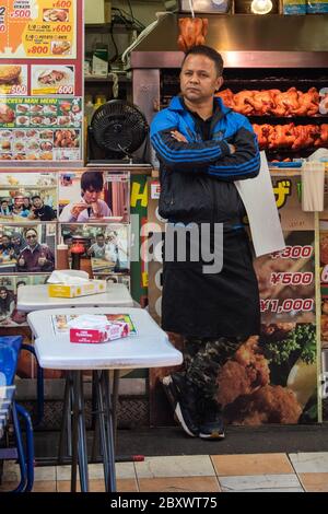 Ein Fastfood-Stallbesitzer vor seinem Stand auf dem Ameyoko-Markt in Tokio, Japan Stockfoto