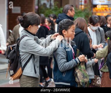 Eine Mutter hilft ihrer Tochter, Haare und Kleidung zu reparieren. Takeshita Street, Harajuku, Tokio, Japan Stockfoto