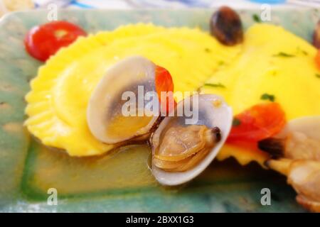 Italienische Pasta, Ravioli, mit Venusmuscheln. Mit Olivenöl, Petersilie und Tomaten gewürzt. Hochwertige Fotos Stockfoto