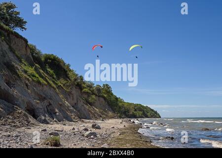 Zwei Paragleiter fliegen an einem sonnigen Tag über die wilde Steilküste am Strand der Ostsee, wunderschöne Landschaft für Outdoor-Sport und Vacatio Stockfoto