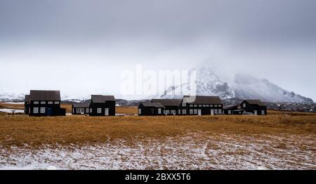 Kleine Hütten und der schneebedeckte Stapellberg bei Hellnar, Snaefellnes Halbinsel in Island Stockfoto
