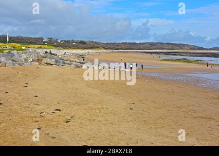 Ein paar Leute in Gruppen, die bei Ebbe am Newton Beach in der Nähe von Porthcawl entlang laufen Stockfoto