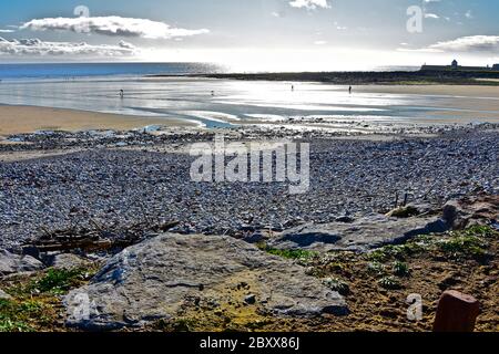 Ein Blick über Sandy Bay, Porthcawl, bei Ebbe. Wellenbrecher & Leuchtturm in der Ferne. Nachmittag niedrige Sonne scheint auf nassem Sand. Stockfoto