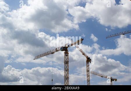 Gelbe Baukräne auf der Baustelle unter blauem und wolkenverwaelterem Himmel Stockfoto