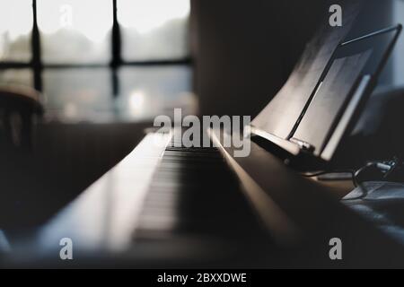 Low-Shot von 88 Tasten einer Tastatur und Noten. Nahaufnahme mit Licht von der Seite Stockfoto