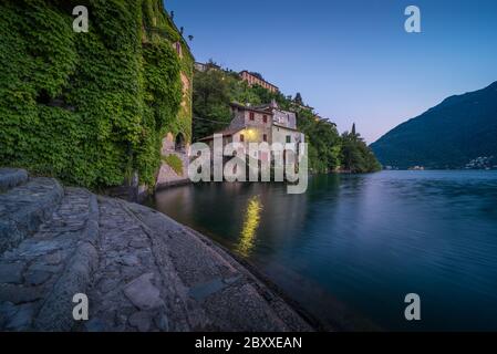 Landschaftlich reizvolle Aufnahme von Nesso am Comer See in Italien mit Steinvordergrund zur blauen Stunde Stockfoto