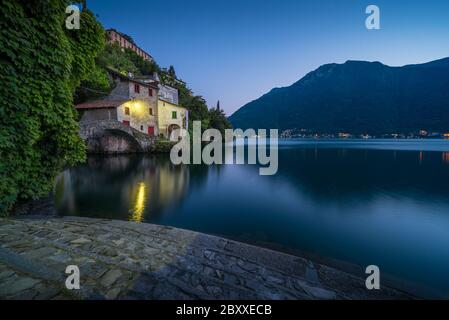 Landschaftlich reizvolle Aufnahme von Nesso am Comer See in Italien mit Steinvordergrund zur blauen Stunde Stockfoto