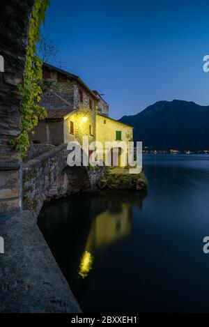 Landschaftlich reizvolle Aufnahme von Nesso am Comer See in Italien mit Steinvordergrund zur blauen Stunde Stockfoto