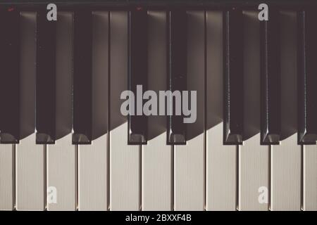 Nahaufnahme von elfenbeinfarbenen schwarzen und weißen Tasten auf einem Klavier von oben mit Schatten Stockfoto